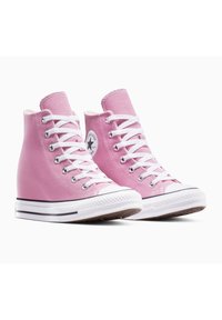 Baskets montantes en toile rose avec lacets blancs, embout en caoutchouc et patch logo noir et blanc sur le côté. Dotées d'une semelle texturée.