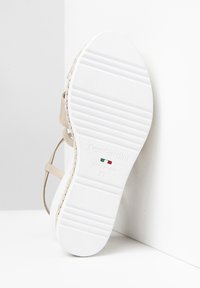 Beige sandal med tynde stropper, vævet detaljer og en hvid tekstureret sål. Har branding prentet på bunden. Str. 37, lavet i Italien.