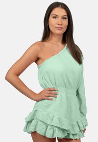 Mintgroene off-shoulder jurk met rimpelige zoom, lichte textuurstof, gathered taille en één lange mouw.