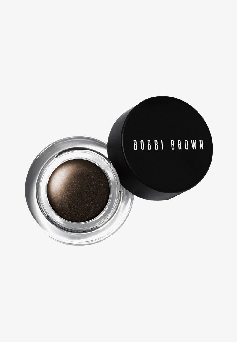 Klein helder glazen potje met donkerbruine crème eyeliner naast het zwarte deksel met de tekst "BOBBI BROWN" in witte letters.