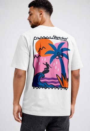 Man wearing a white T-shirt with colorful surf-themed graphic showing a surfer, blue palm tree, orange sun, and "Neverless" text on the back.