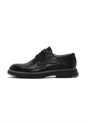 Chaussures en cuir noir à lacets avec bout arrondi, surface texturée et semelle en caoutchouc contrastante. Présente des coutures discrètes et un design élégant.
