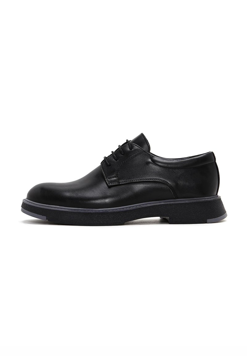 Zapatos de cuero negro con cordones, con punta redonda, superficie texturizada y suela de goma de contraste. Presenta costuras sutiles y un diseño elegante.