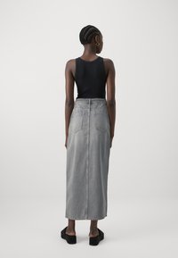 Svart tettsittende tanktop, høy midje lysegrå denim maxiskjørt, to baklommer, glatt tekstur, paret med svarte platå sandaler.