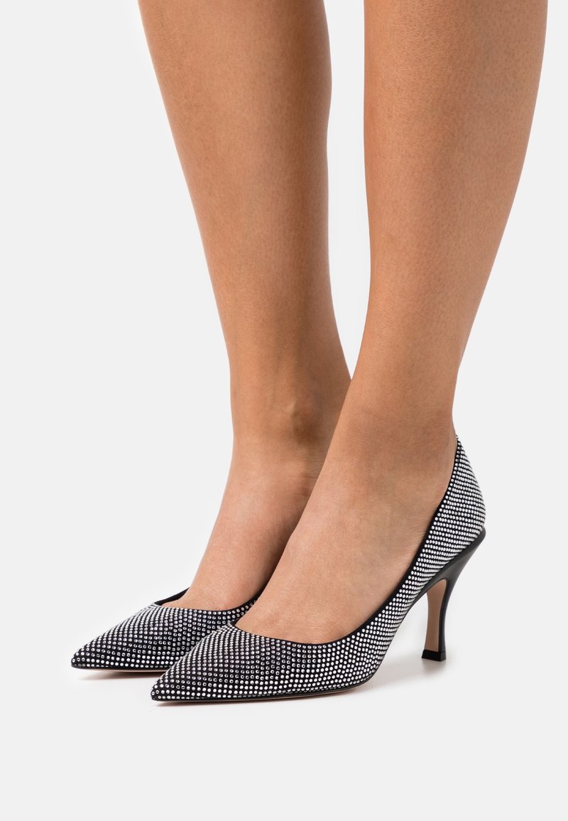 Escarpins noirs et blancs à bout pointu avec un motif à carreaux et un petit talon aiguille, fabriqués en matériau lisse avec une finition brillante.