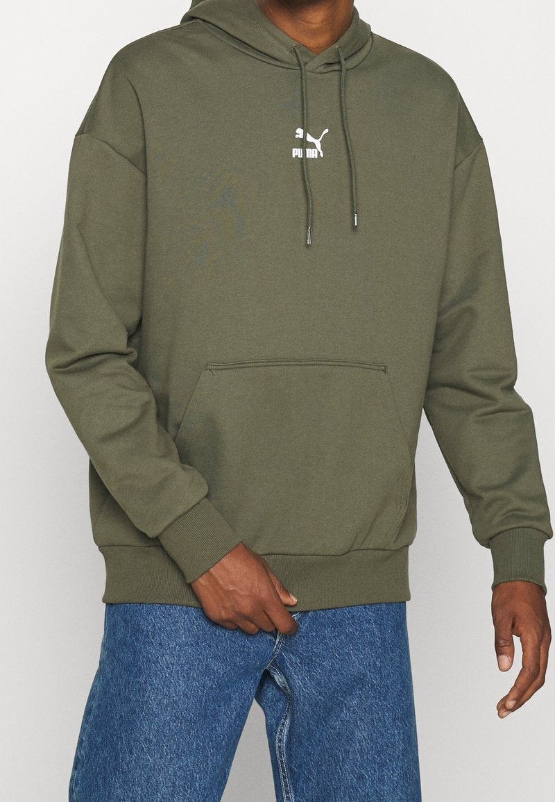 Sudadera con capucha de color verde oliva con un bolsillo canguro, cordones y un logo blanco en el pecho. Confeccionada con tela suave y cómoda.