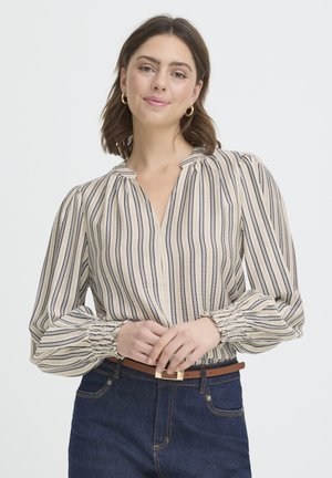 Beige and navy striped blouse with a V-neck, puffed sleeves, and gathered cuffs. Worn with dark denim and a brown belt featuring a gold buckle.