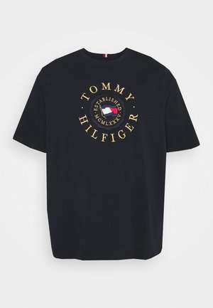 T-shirt noir à manches courtes avec texte doré "Tommy Hilfiger" et logo circulaire présentant un drapeau rouge, blanc et bleu au centre.