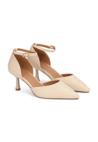 Escarpins beiges à bout pointu avec une fine bride à la cheville et un petit talon carré. Finition en cuir lisse avec une texture mate et sans motifs visibles.