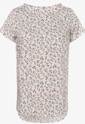 Blouse blanche à manches courtes avec un petit motif floral rose, bleu et vert, encolure ronde et ourlet légèrement arrondi.