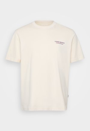 Krémové bavlněné tričko s kulatým výstřihem, krátkým rukávem a malým modrým a červeným potiskem "ATELIER ORIGINALS" na hrudi.