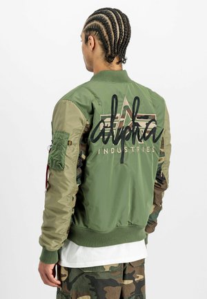 Olivgrüne Bomberjacke mit Camouflage-Ärmeln. Verfügt über ein gesticktes "alpha industries"-Logo, gerippte Bündchen und eine große Utility-Tasche.