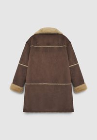 Manteau en daim marron avec un col et des poignets en fausse fourrure beige. Présente des coutures contrastées et une coupe décontractée et oversize. Vue de dos.
