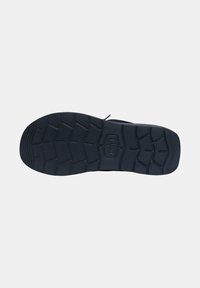 Suela de zapato de goma negra con un patrón texturizado, que presenta profundos surcos para tracción y un diseño de punta ligeramente redondeada.