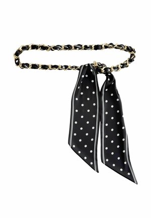 Čierno-zlatý reťazový opasok s čiernym hodvábnym šálom s bielymi bodkami a lemom, zviazaný do mašľe.