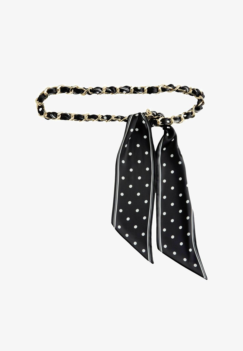 Melns un zelta ķēdes jostas ar melnu zīda šalli, kas rotāta ar baltām polka punktiem un apmali, sasieta lokā.