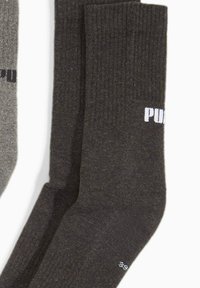 Dwie pary złożonych skarpetek załogowych, jedna ciemnoszara z białym napisem, druga jasnoszara z czarnym napisem, na białym tle.