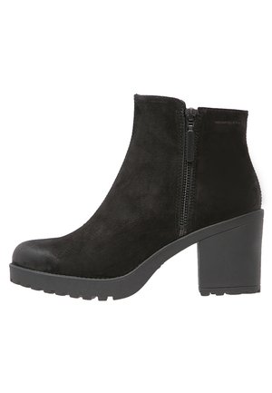 Schwarzer Knöchelstiefel aus Wildleder mit niedrigem Schaft, seitlichem Reißverschluss und klobigem schwarzen Absatz mit strukturiertem Profil.