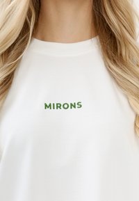 Weißes Baumwoll-T-Shirt mit grünem besticktem Schriftzug "MIRONS." Einfaches Design mit Rundhalsausschnitt und glatter Textur.