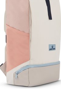 Mochila rectangular con paneles beige, rosa claro y gris, con un bolsillo frontal azul con cremallera y un pequeño parche con el logo "Johnny Urban".