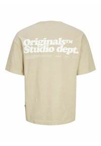 Beige cotton T-shirt with a relaxed fit, featuring large white text on the back: "Originals™ Studio dept." and additional brand details.