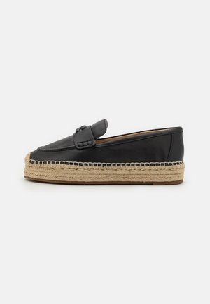 Mocassins en cuir noir avec semelle en jute de style espadrille, présentant une texture lisse, des détails cousus et une sangle décorative sur le dessus.