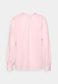 Lichtroze langemouwen shirt met een geplooide achterkant, knoopmanchetten en een zachte textuur, met subtiele verticale strepen.