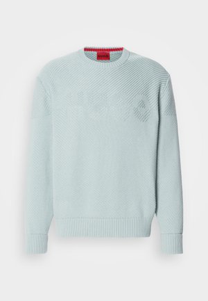 Svijetloplavi pleteni pulover s teksturiranim chevron uzorkom, rebrastim manžetama i crvenom etiketom s imenom brenda "HUGO" unutar ovratnika.