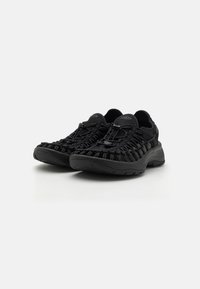 Scarpe sportive nere con design superiore intrecciato, suola in gomma e lacci elastici. Caratterizzano un colletto imbottito e una superficie testurizzata.