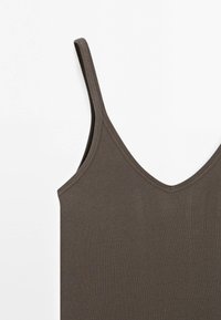 Bruine geribbelde tanktop met verstelbare bandjes en een V-halslijn. Beschikt over een zachte textuur en een aansluitende pasvorm.