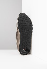 Sneaker marrone chiaro con tomaia strutturata e suola in gomma nera con motivo del battistrada. Include un branding discreto e dettaglio con la bandiera italiana.