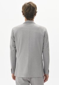 Grå kavaj, strukturerad tyg, enkel bakre slits, flikslag, knäppta manschetter, med skräddarsydd design.