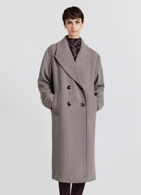 Cappotto doppiopetto in lana grigia con grandi rever, due tasche frontali e bottoni neri. Senza fodera, con vestibilità comoda e lunghezza fino a metà polpaccio.