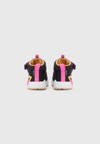 Zwarte en roze Gore-Tex sneakers met witte gestructureerde zolen, gezien vanaf de achterkant op een effen witte achtergrond.