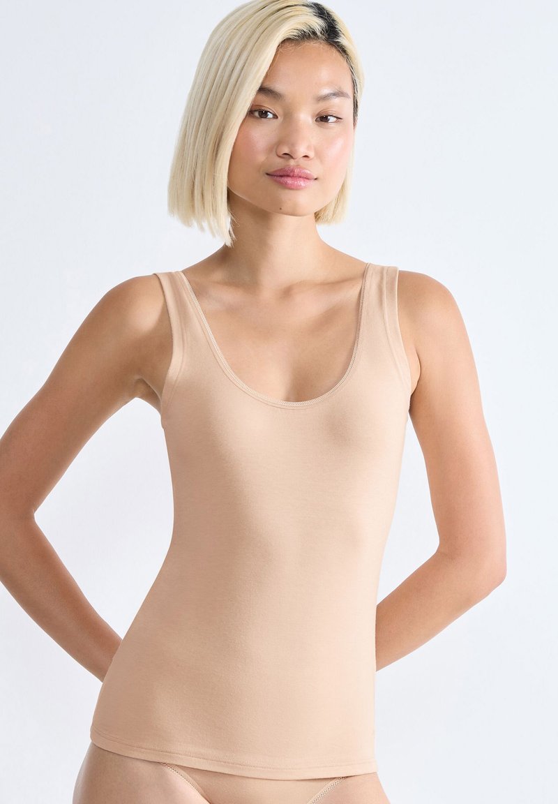 Top beige senza maniche con spalline larghe, scollatura arrotondata e texture liscia. Design aderente, stile basic, minimi dettagli di cucitura.