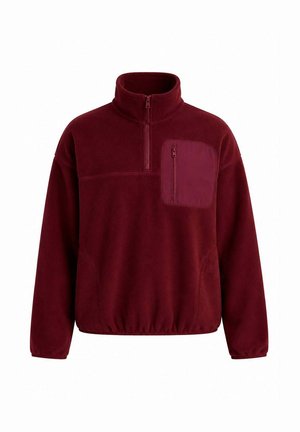 Pull polaire bordeaux avec demi-fermeture éclair, col montant, ourlet élastique et poche poitrine zippée côté gauche.