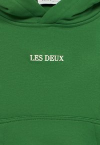 Πράσινο φούτερ με κουκούλα από απαλό ύφασμα, με τσέπη καγκουρό, ριμπ μανσέτες και λευκό κείμενο «LES DEUX» στο κέντρο μπροστά.