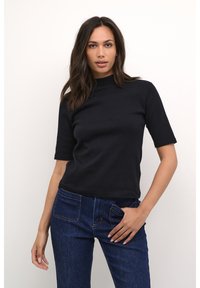 Black ribbed short-sleeve top with a high neckline, paired with blue denim jeans featuring front and back pockets.