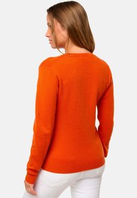 Pull en maille orange à manches longues, col rond et ourlet côtelé. Texture lisse et design ajusté, présenté de l'arrière.