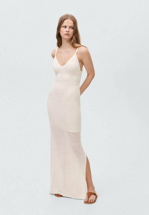 Brede gebreide maxi-jurk in off-white met een V-hals, spaghettibandjes en een zij-split. Heeft een gestructureerd patroon en een aansluitend lijfje, dat vloeiend naar beneden loopt.