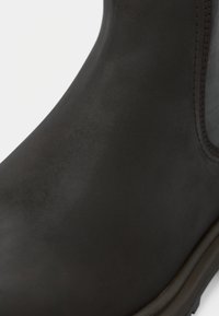 Schwarzer Gummistiefel mit glatter Oberfläche, eleganten Design und seitlichen elastischen Einsätzen für ein einfaches Anziehen. Gummisohle, minimalistische Akzente.