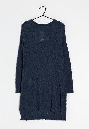 Pull en maille texturée bleu foncé à manches longues suspendu sur un cintre noir contre un fond blanc.