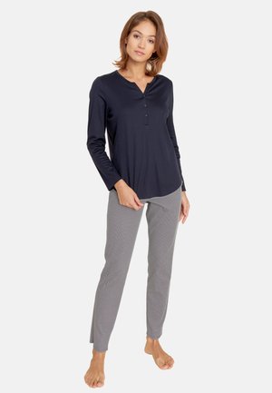 Navy long-sleeve top with button placket paired with grey patterned trousers featuring tapered legs and a soft fabric texture.