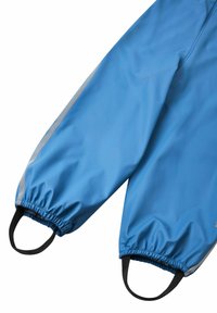 Chaqueta impermeable azul con puños elásticos, franja reflectante y asas negras en los extremos de las mangas. Textura suave.