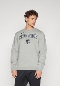Grå hettegenser med rund hals, lange ermer og "NEW YORK" tekst med logo. Laget av mykt stoff med ribbede mansjetter.
