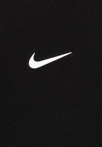 Schwarzes T-Shirt aus Stoff mit einem weißen Nike Swoosh-Logo. Die Textur ist glatt mit einem feinen Webmuster. Standard Crewneck-Design.