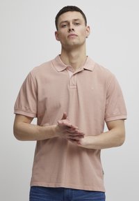 Kortermet polo-skjorte i myk rosa bomull, med en klassisk krage og subtil logo-broderi på brystet. Standard passform med en teksturert finish.