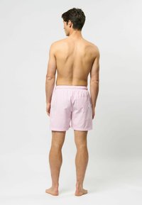 Rosa rutete svømmetights med elastisk midje, enkelt baklomme og avslappet passform. Overflaten er glatt og lett.