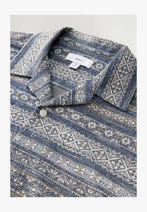 Blaues Poloshirt mit Muster und Kragen, das aufwendige geometrische Designs in Creme und Beige zeigt und eine Knopföffnung am Hals hat.