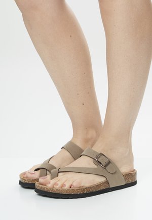 Sandales en liège beige avec une large sangle sur le pied et un design croisé. Présentent un accent de boucle en métal pour un ajustement et un confort réglables.